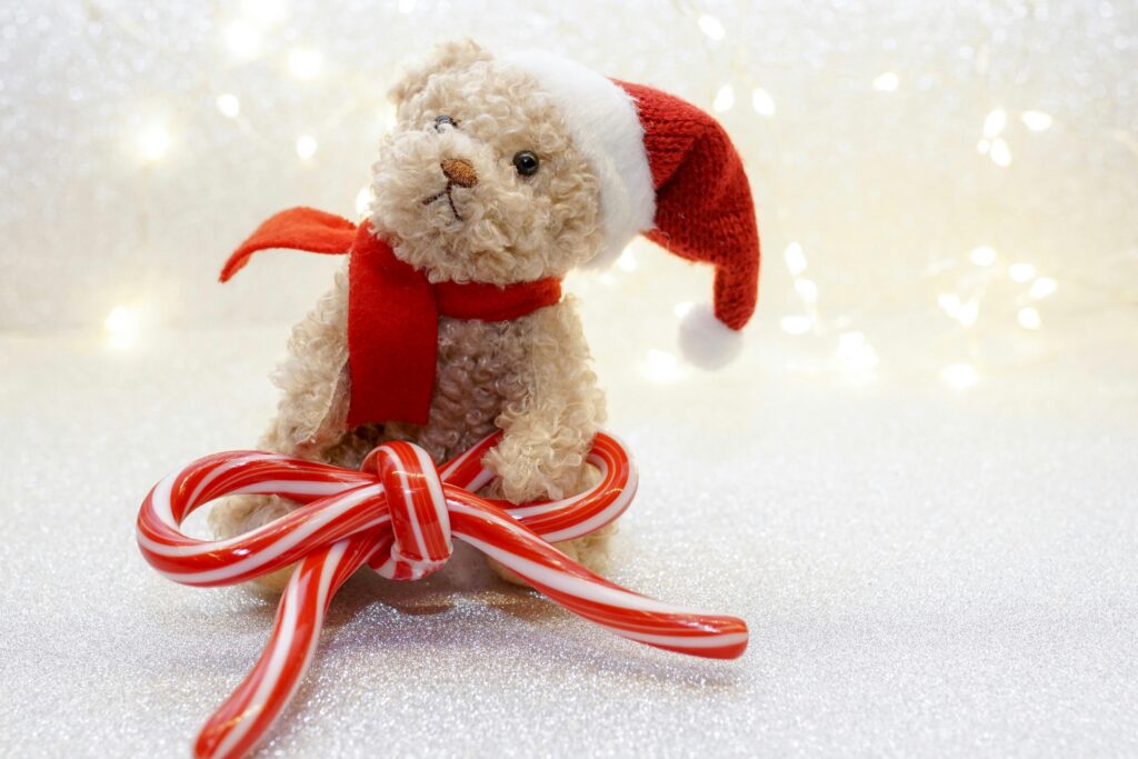 A cute teddy bear in a Santa hat with candy cane decoration, perfect for holiday themes.